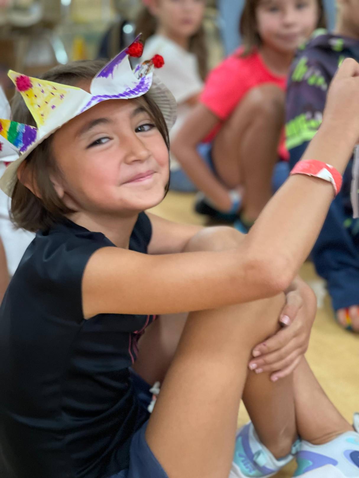 A young girl with a crown joyfully holds a toy
